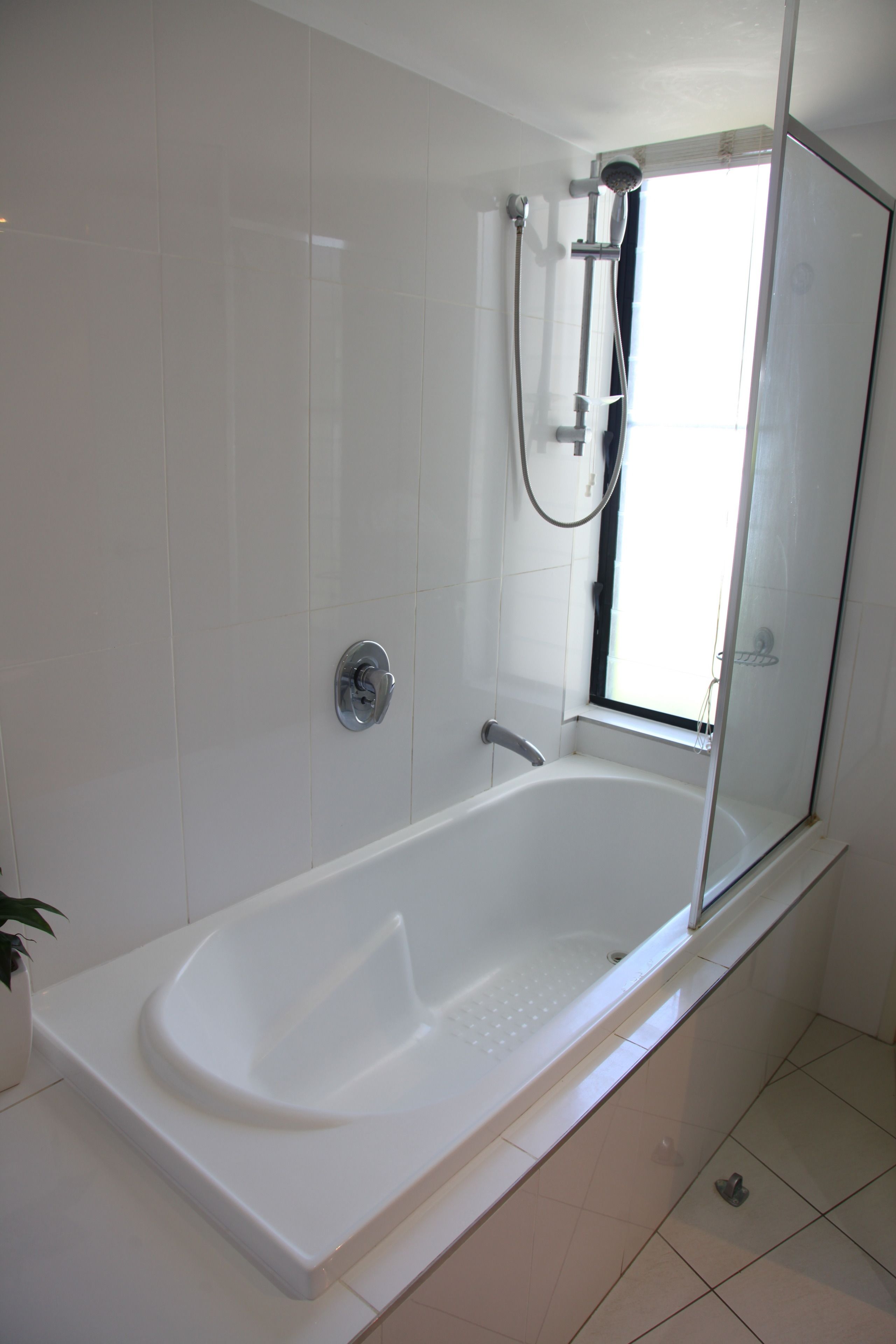 Une salle de bain moderne avec une baignoire sur pieds, une douche à parois de verre et une fenêtre laissant entrer la lumière naturelle.