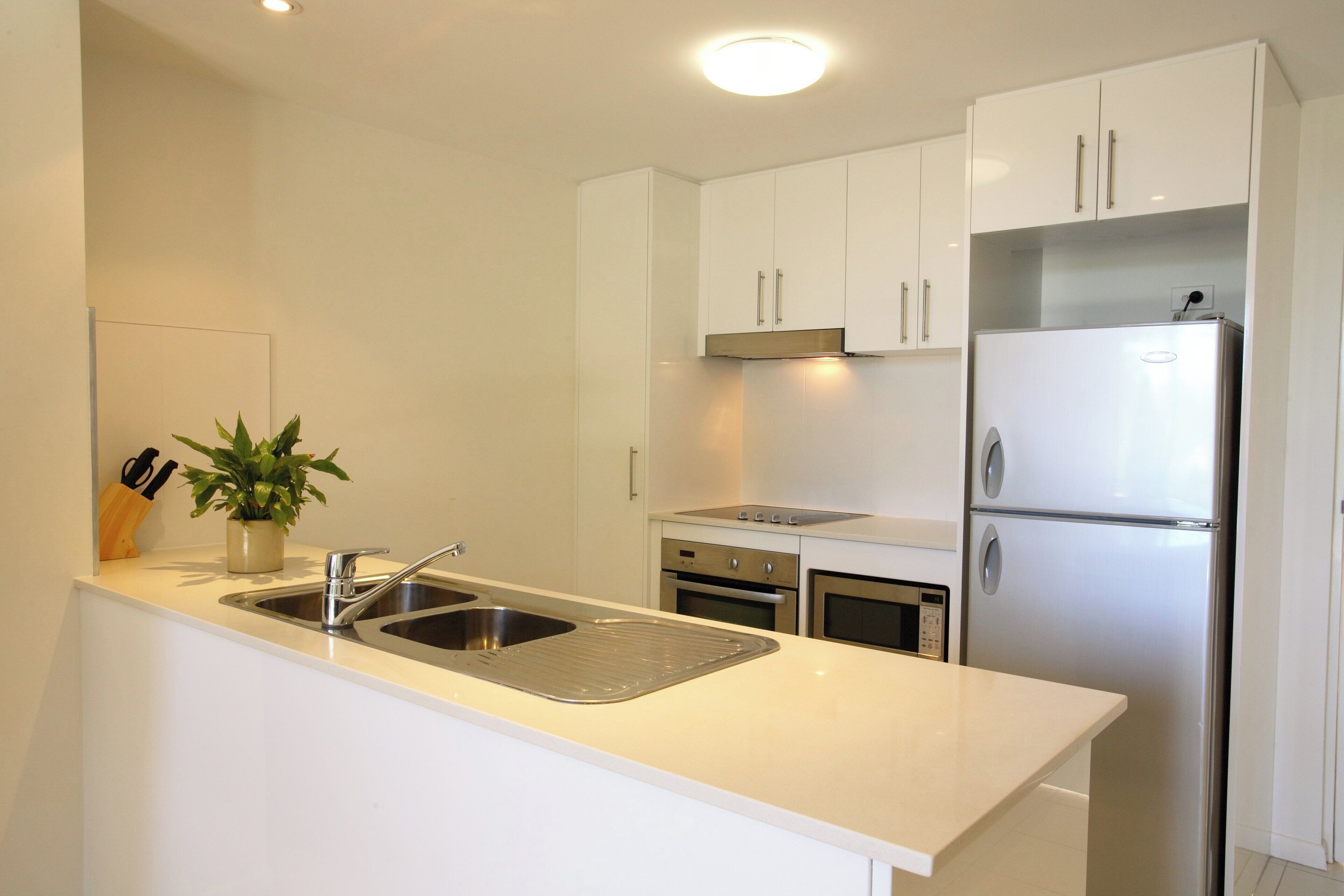 Una cocina moderna con armarios blancos, electrodomésticos de acero inoxidable y un horno empotrado.
