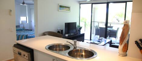 Een moderne keuken met een vaatwasser, een dubbele spoelbak en een eethoek met een tafel en stoelen.