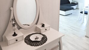 A white vanity with a large mirror, a decorative hairbrush, and a small black purse on the counter. - Logos Guesthouse (Okrug)
