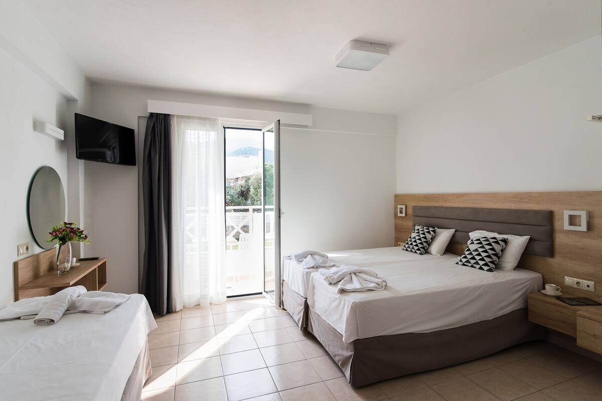 Ein Hotelzimmer mit Bett, Fernseher, Schreibtisch und Blick ins Freie.