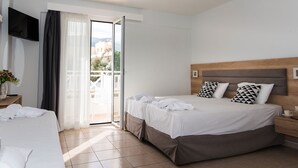 A hotel room with a bed, a TV, a bedside table, and a view of the outdoors. - Vagelis Comfort Apartments (Hersonissos)