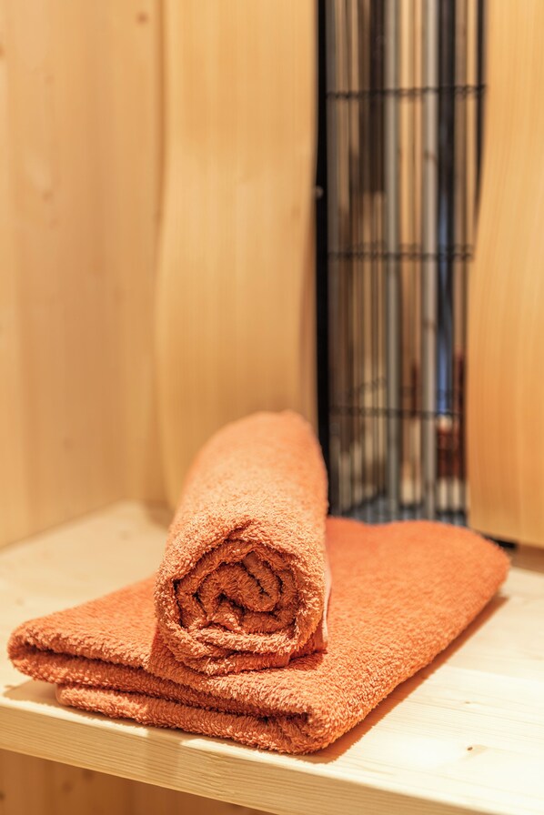 A rolled orange towel on a wooden surface in a room with a metal cage structure in the background.