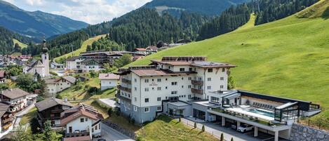 Un hôtel moderne doté d’une piscine, situé dans une région vallonnée, entourée de verdure et de montagnes.