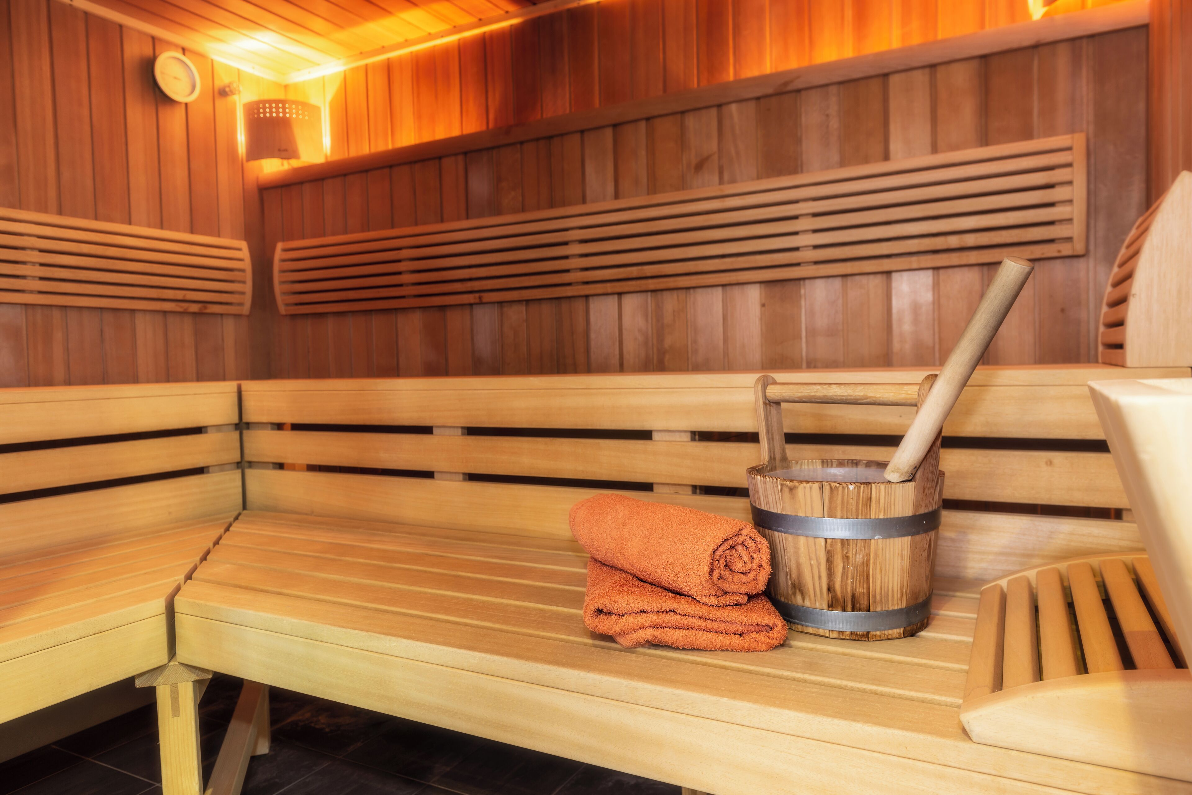 A wooden sauna bench with a towel and a wooden bucket.