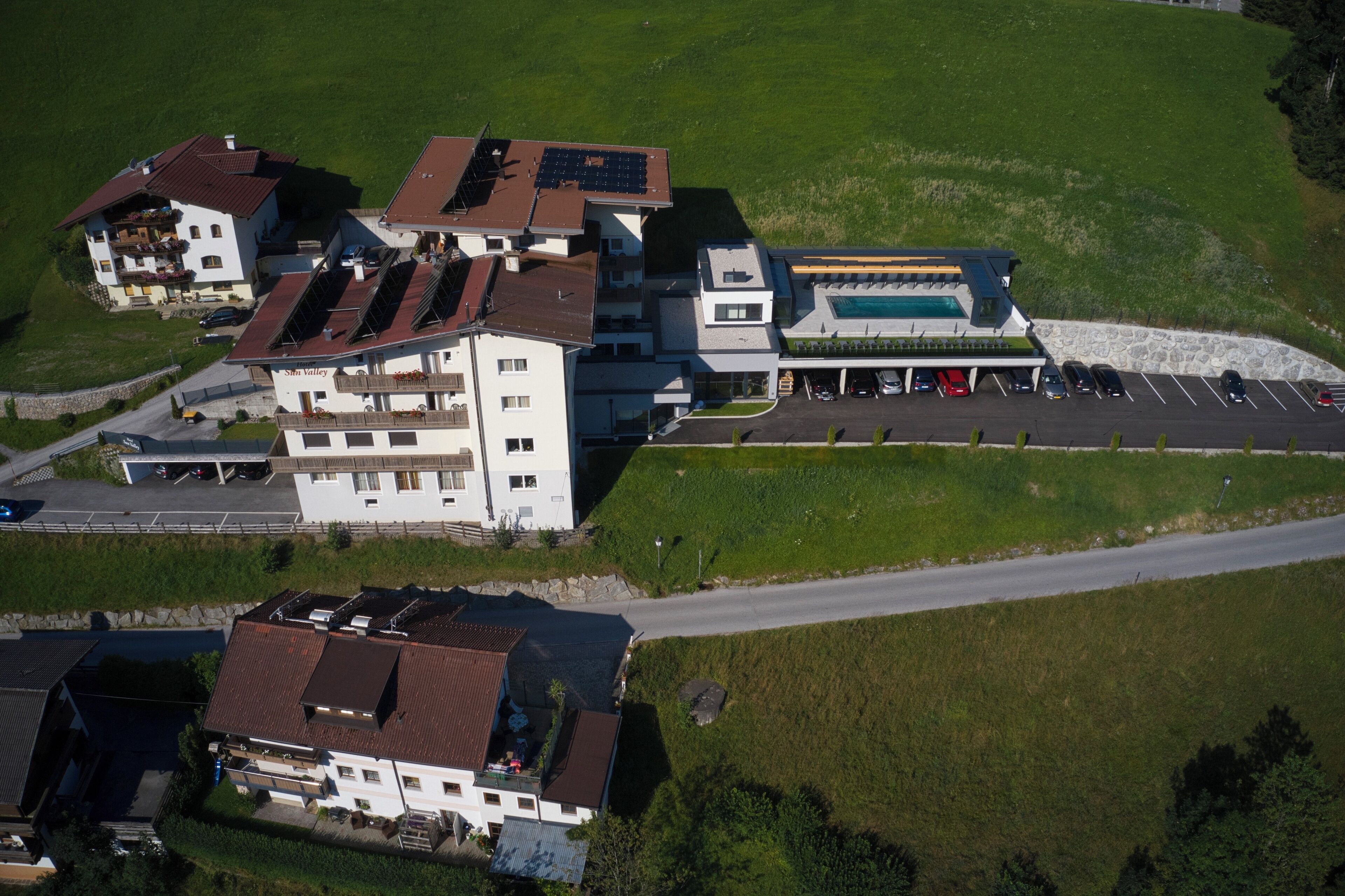 Vista aérea de un complejo hotelero con varias edificaciones, piscina y estacionamiento.