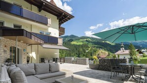 Eine Terrasse mit Gartenmöbeln, einem Esstisch und Blick auf eine Berglandschaft.