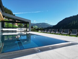 A modern pool area with a clear view of mountains and a house in the background. - Sun Valley - Wildschönau (Wildschönau)