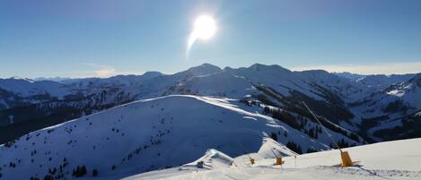 A snow-covered mountain slope with ski tracks and a clear sky.