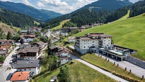 Ein Dorf an einem Hang mit traditioneller und moderner Bebauung, einer Hauptstraße und einem Parkplatz.