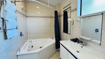 A bathroom with a bathtub, a sink, and a mirror.