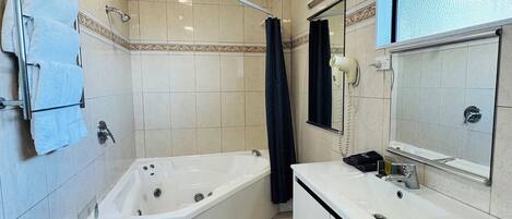 Un baño con bañera, lavabo y espejo.