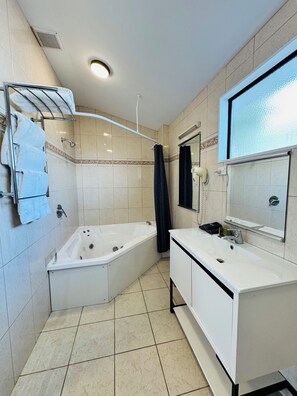 A bathroom with a bathtub, a sink, and a mirror.