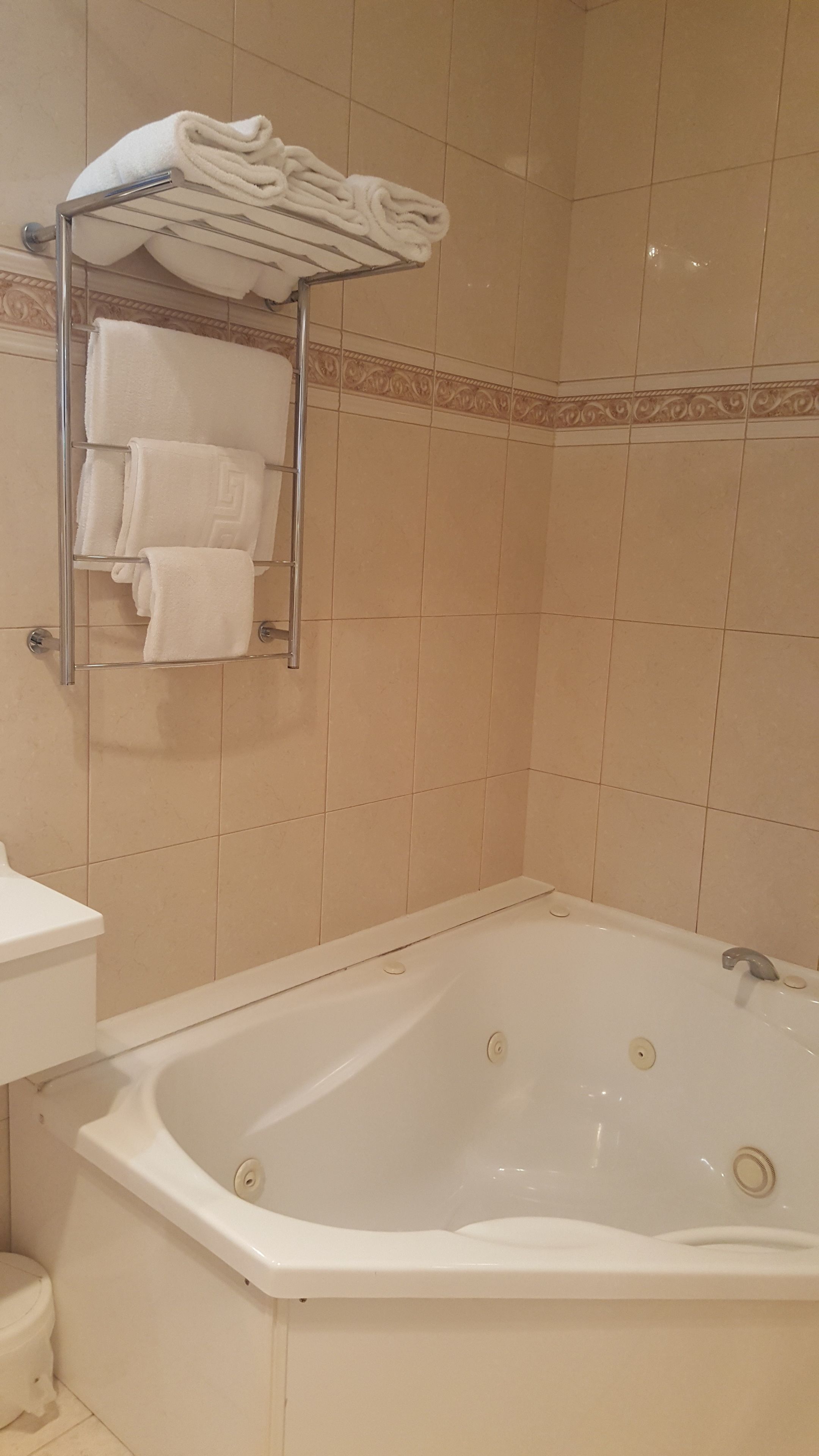 A bathroom with a bathtub, a towel rack with folded towels, and a toilet.