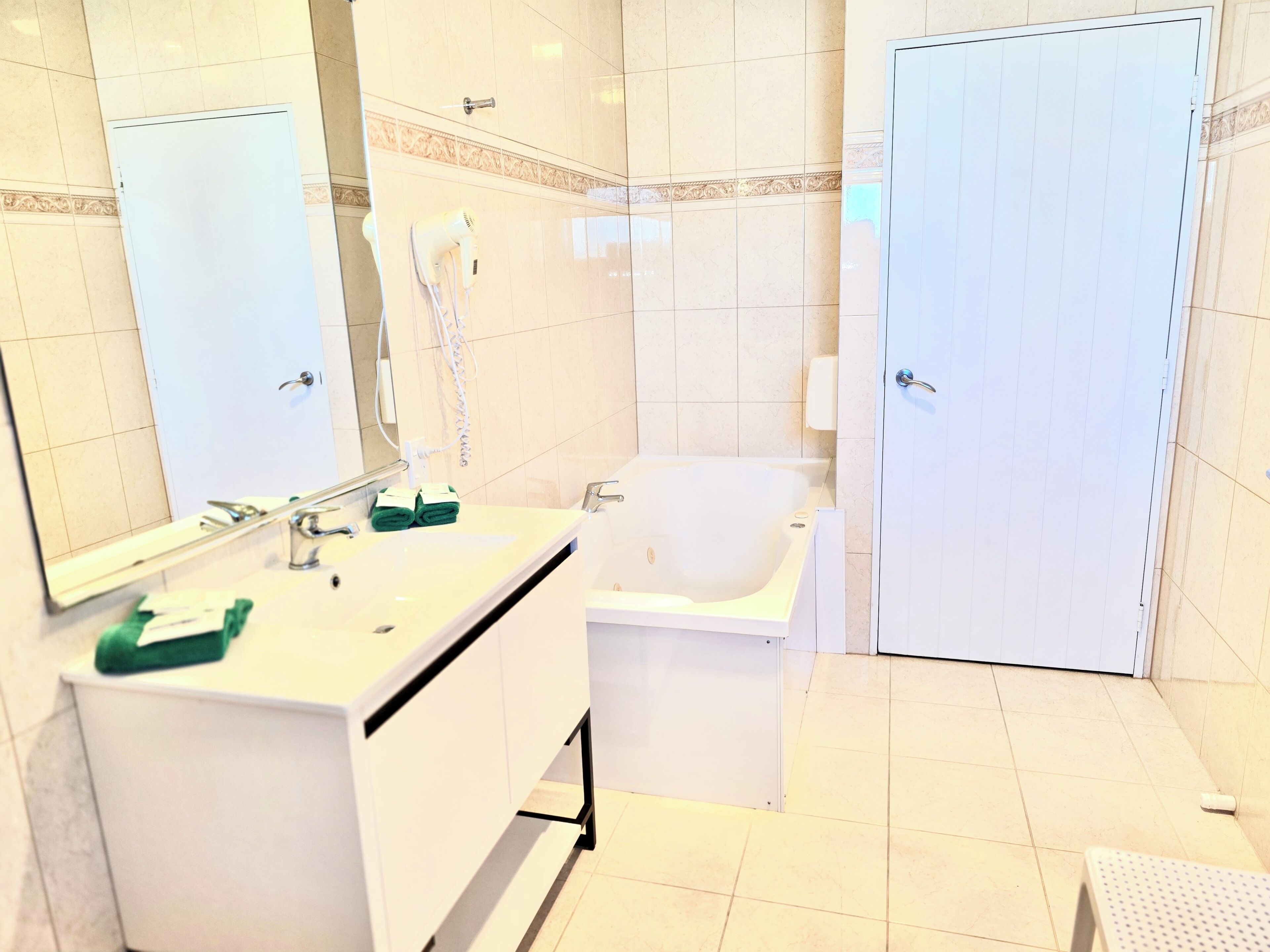A bathroom with a white sink, mirror, and a bathtub.
