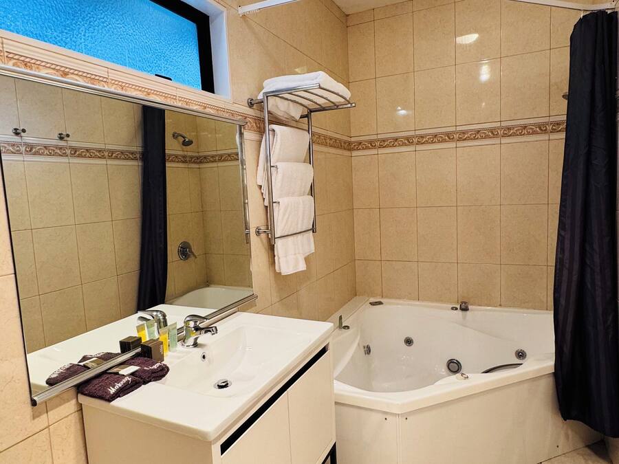 Une salle de bain équipée d’une baignoire, d’un lavabo, d’un miroir et d’un porte-serviettes.
