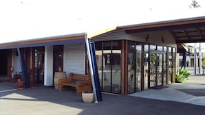 En byggnad med ett takförsett utomhusområde med sittplatser och en butiksfasad av glas.