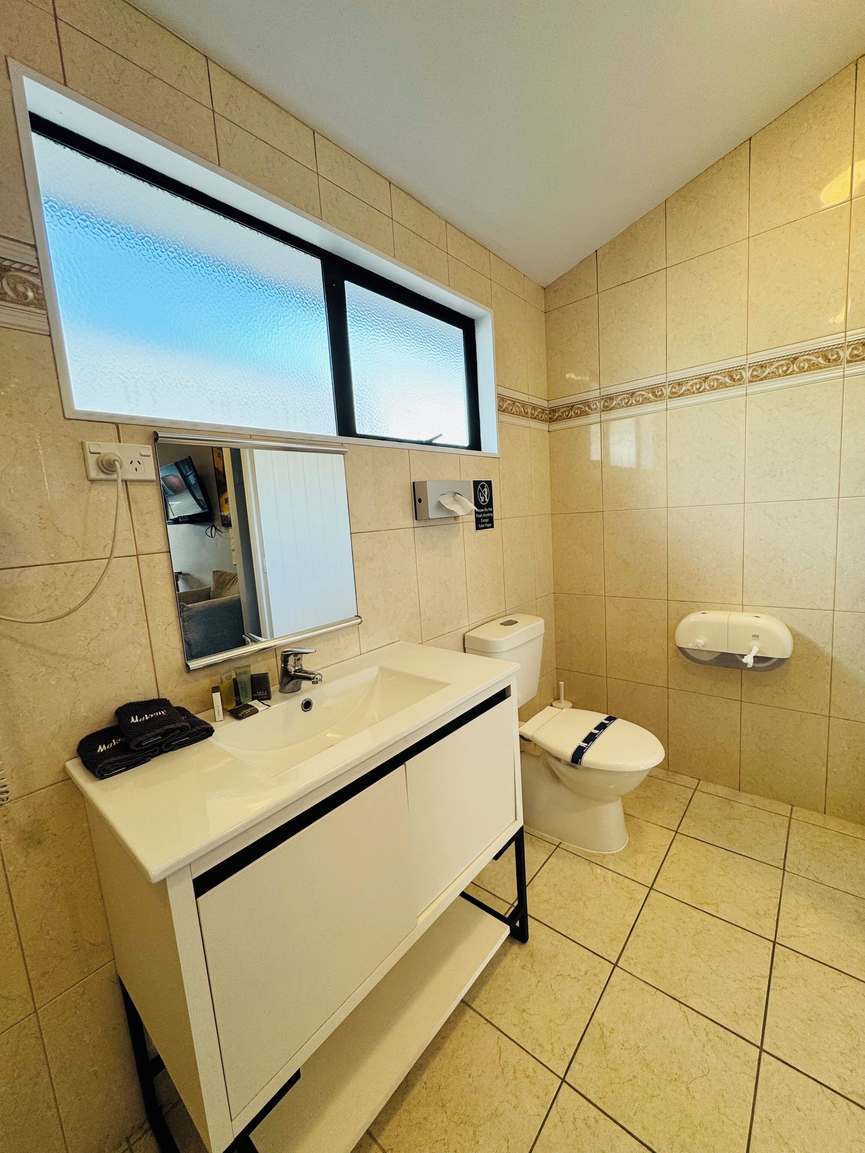 A modern bathroom with a white sink, mirror, and toilet.