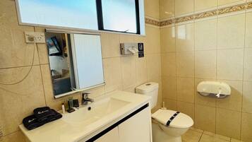 A modern bathroom with a white sink, mirror, and toilet.