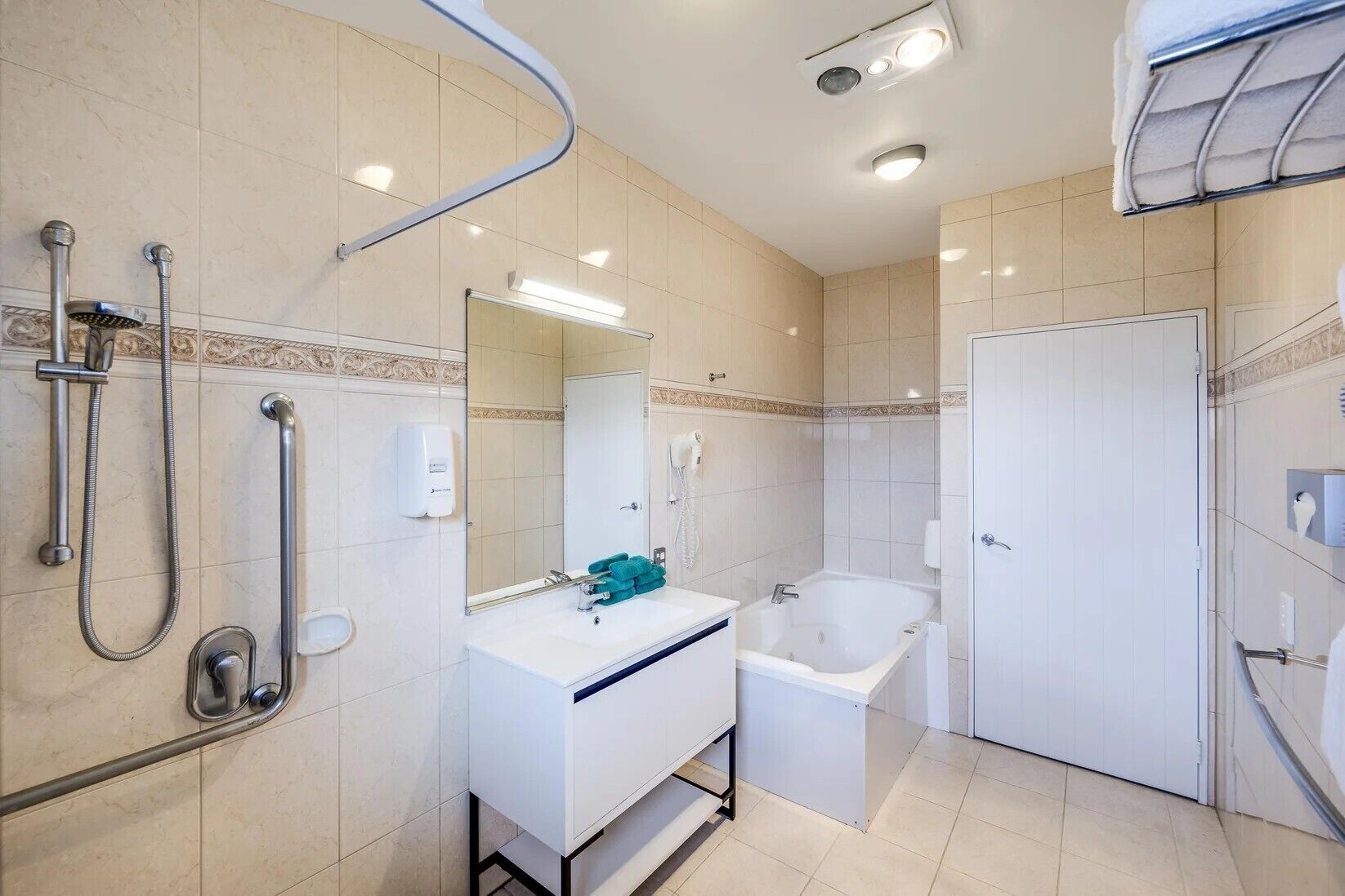 A modern bathroom with a bathtub, shower, and hand dryer.