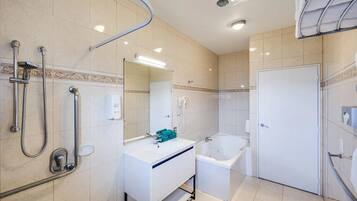 A modern bathroom with a bathtub, shower, and hand dryer.