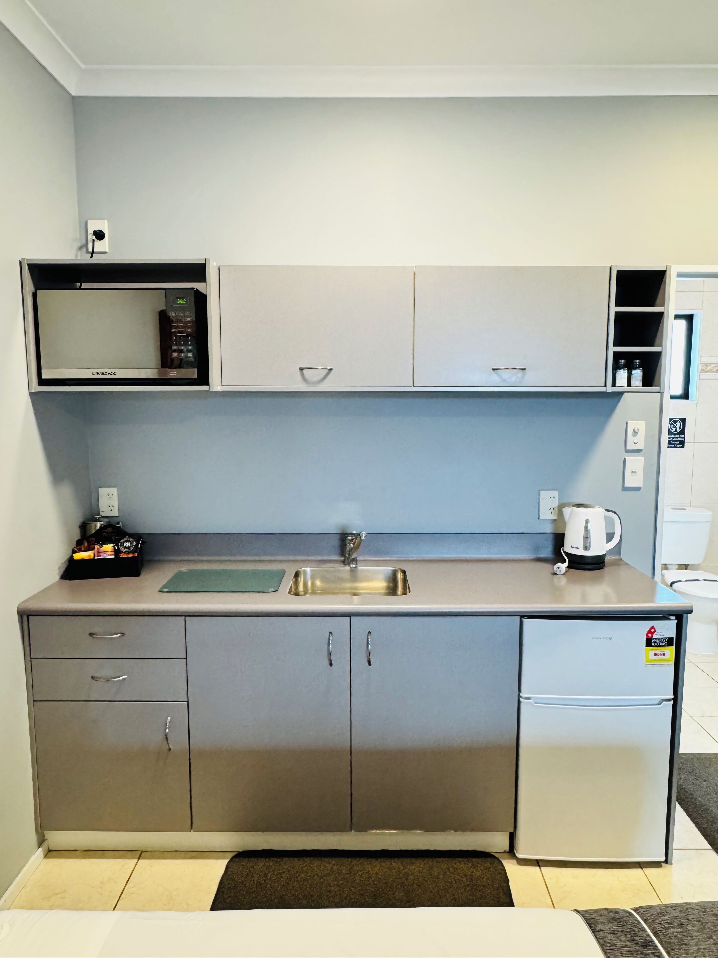 A compact kitchen with a microwave, sink, and a small refrigerator.