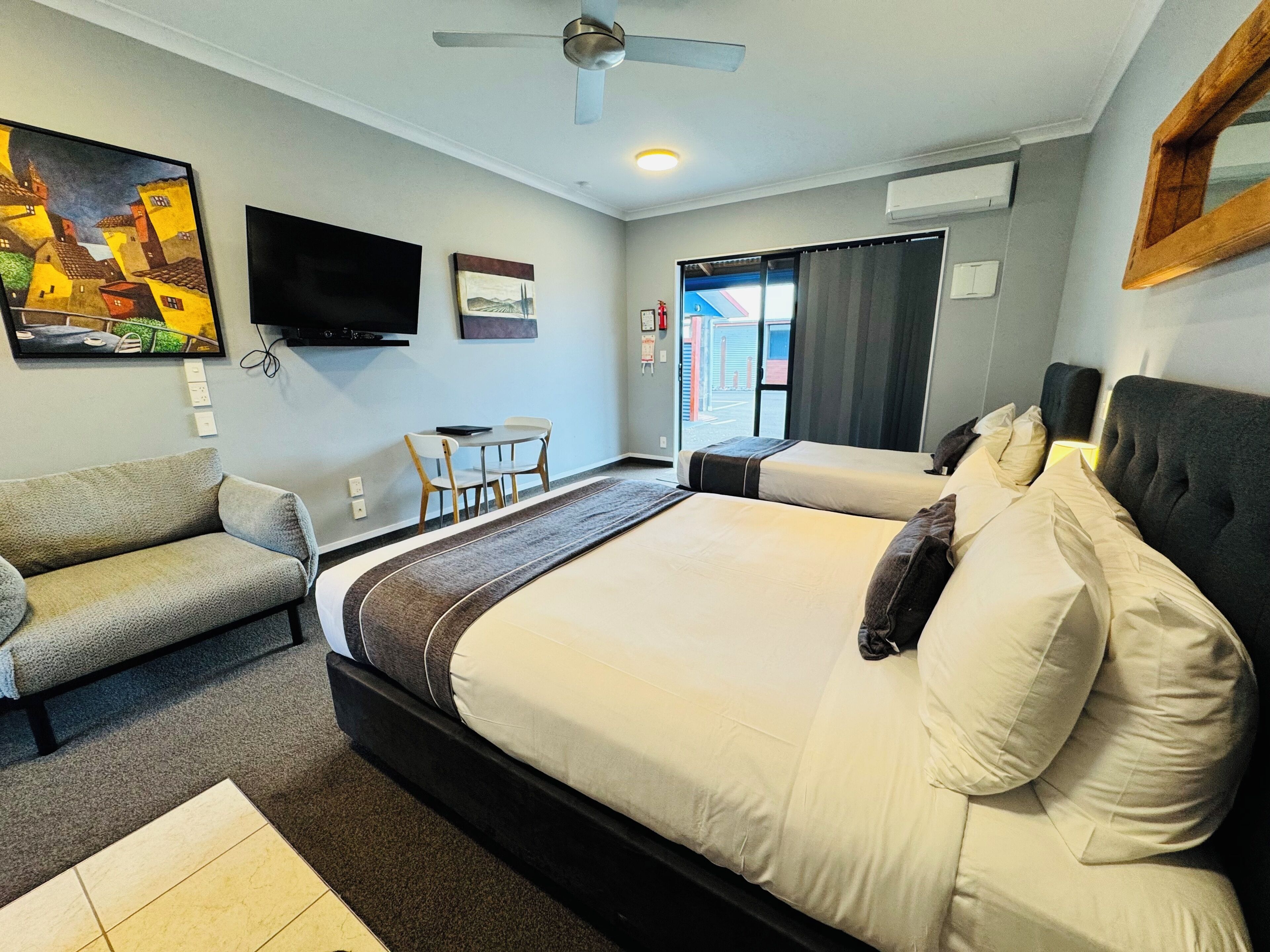 Een hotelkamer met een groot bed, een slaapbank, een bureau met stoelen, een flatscreen-televisie en kunstwerken aan de muur.