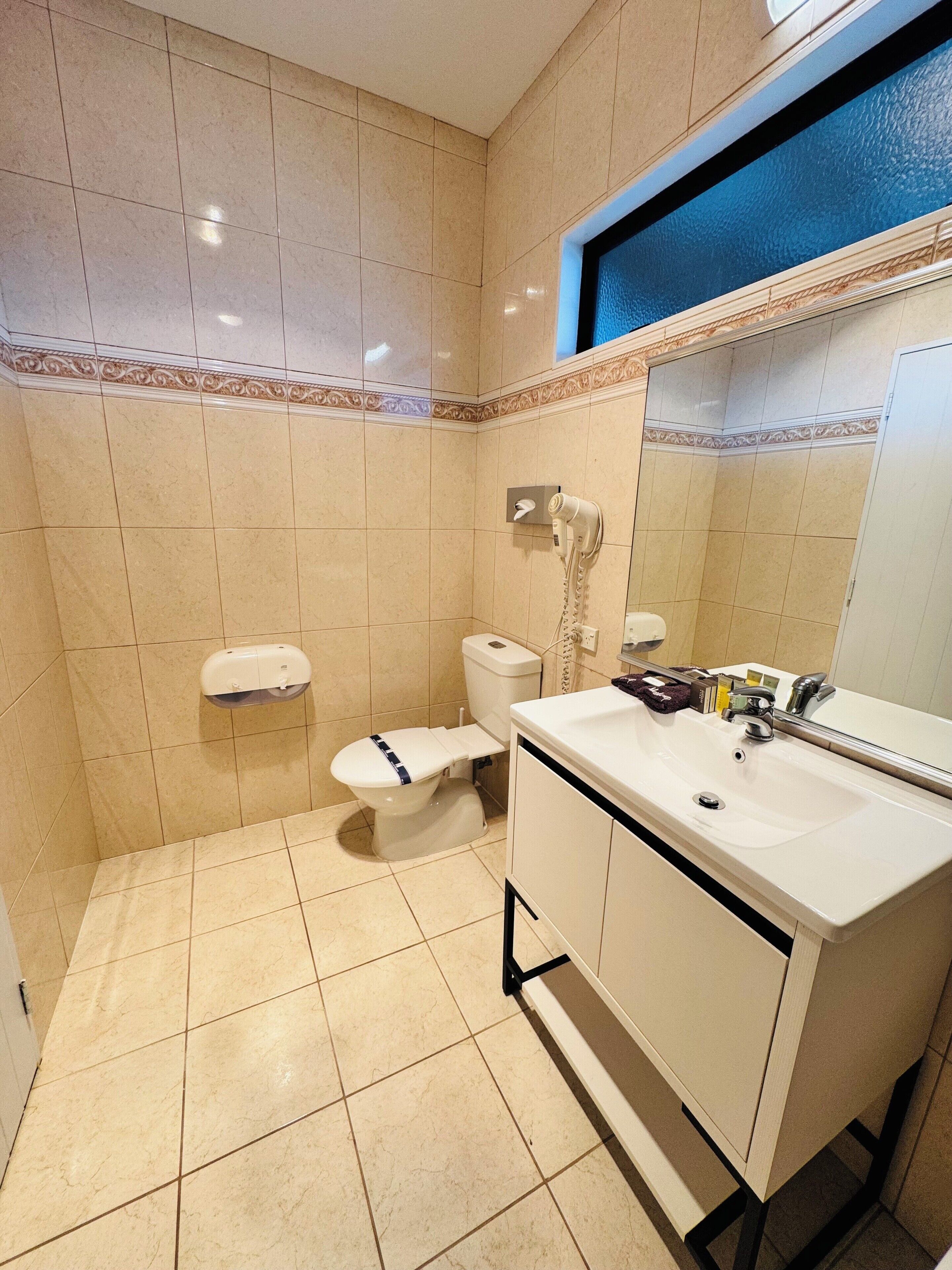 Un baño con inodoro, lavabo y secador de manos.