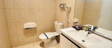 Un baño con inodoro, lavabo y secador de manos.