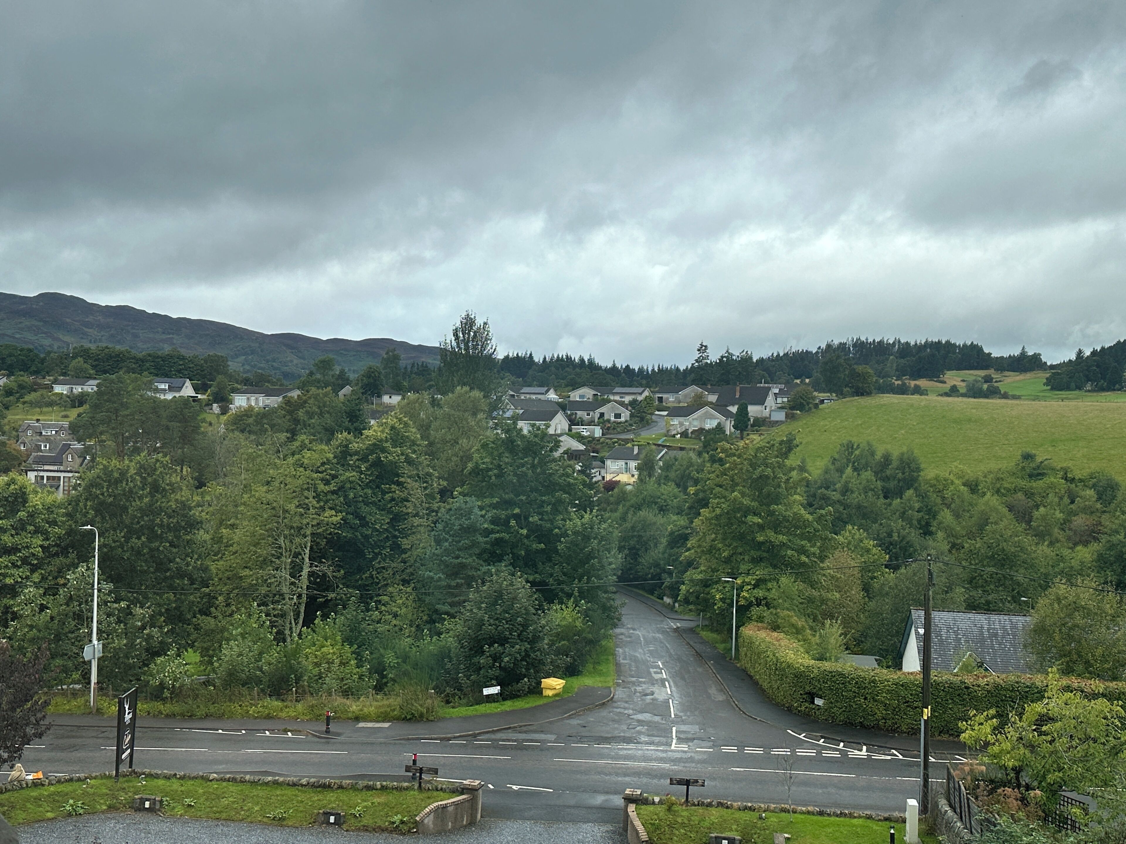 A residential area with houses, a road, and a hill in the background.