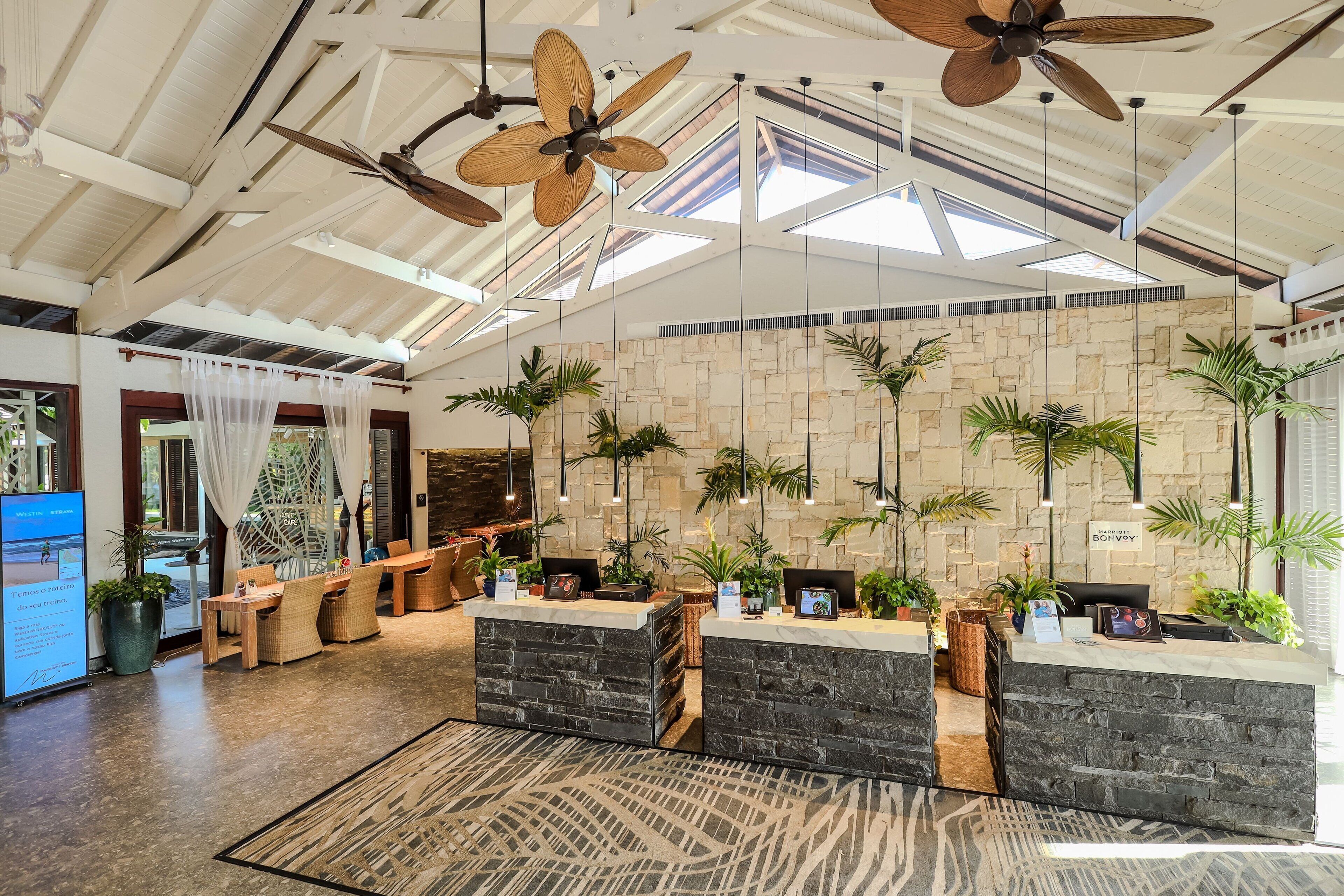 Un'ampia hall con soffitto alto, pareti in pietra e una reception.
