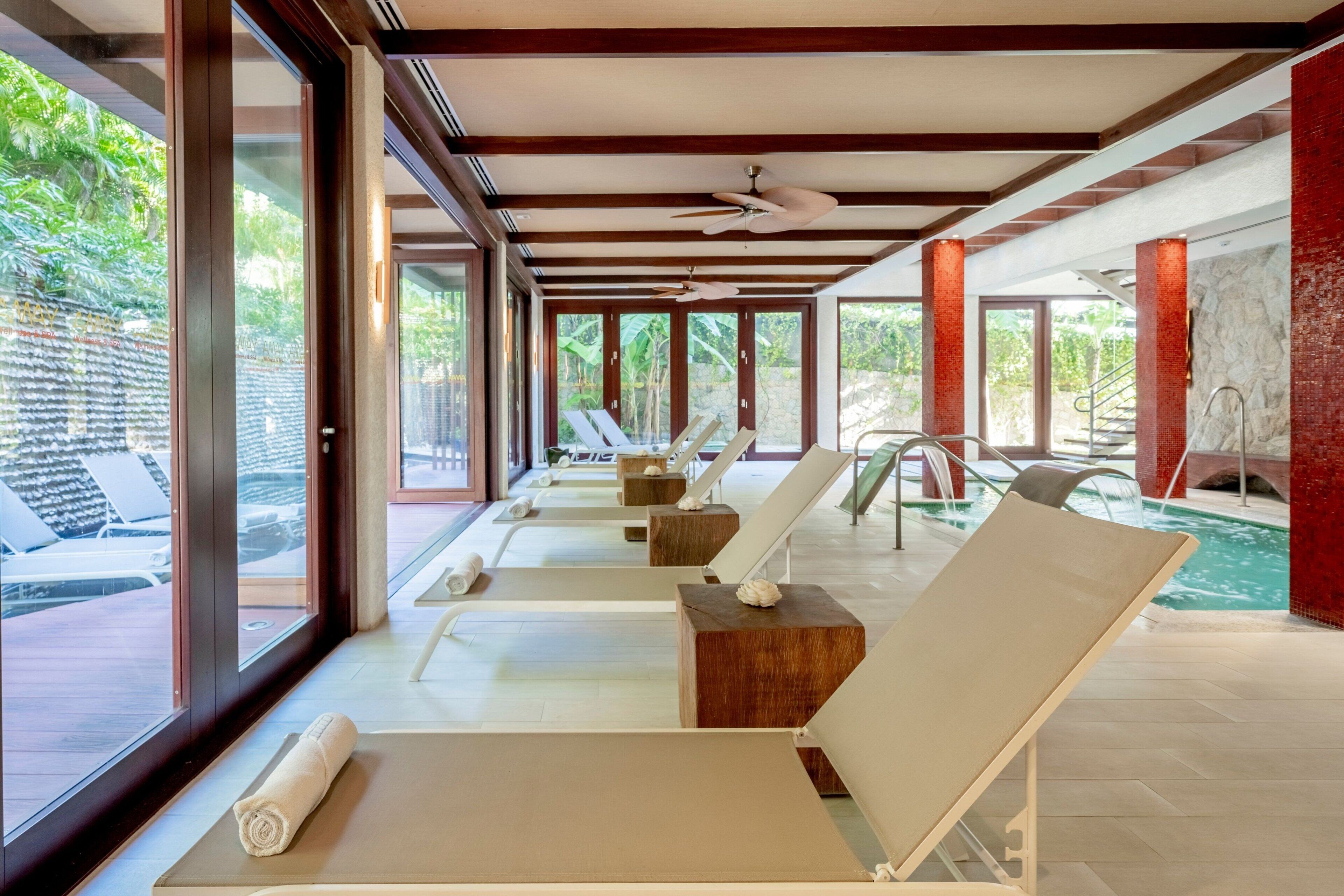 Uma área de spa com espreguiçadeiras, piscina e vista para o exterior.