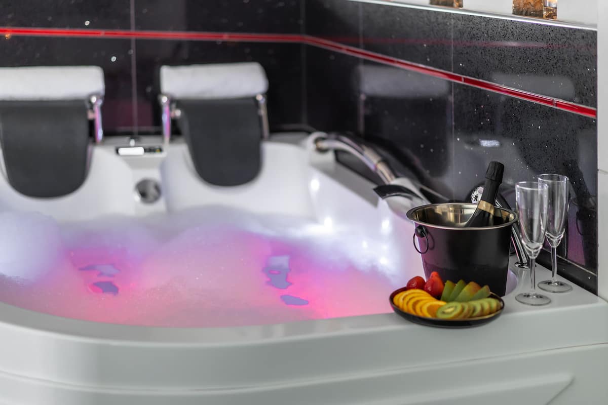 A spa tub with a pink light, a fruit bowl, and two glasses.