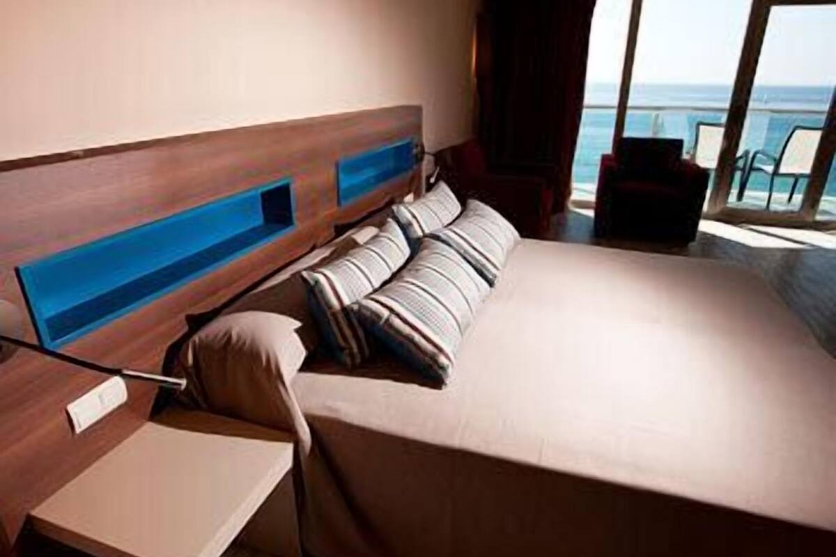 Habitación de hotel moderna con una cama grande, un escritorio y vista al océano.