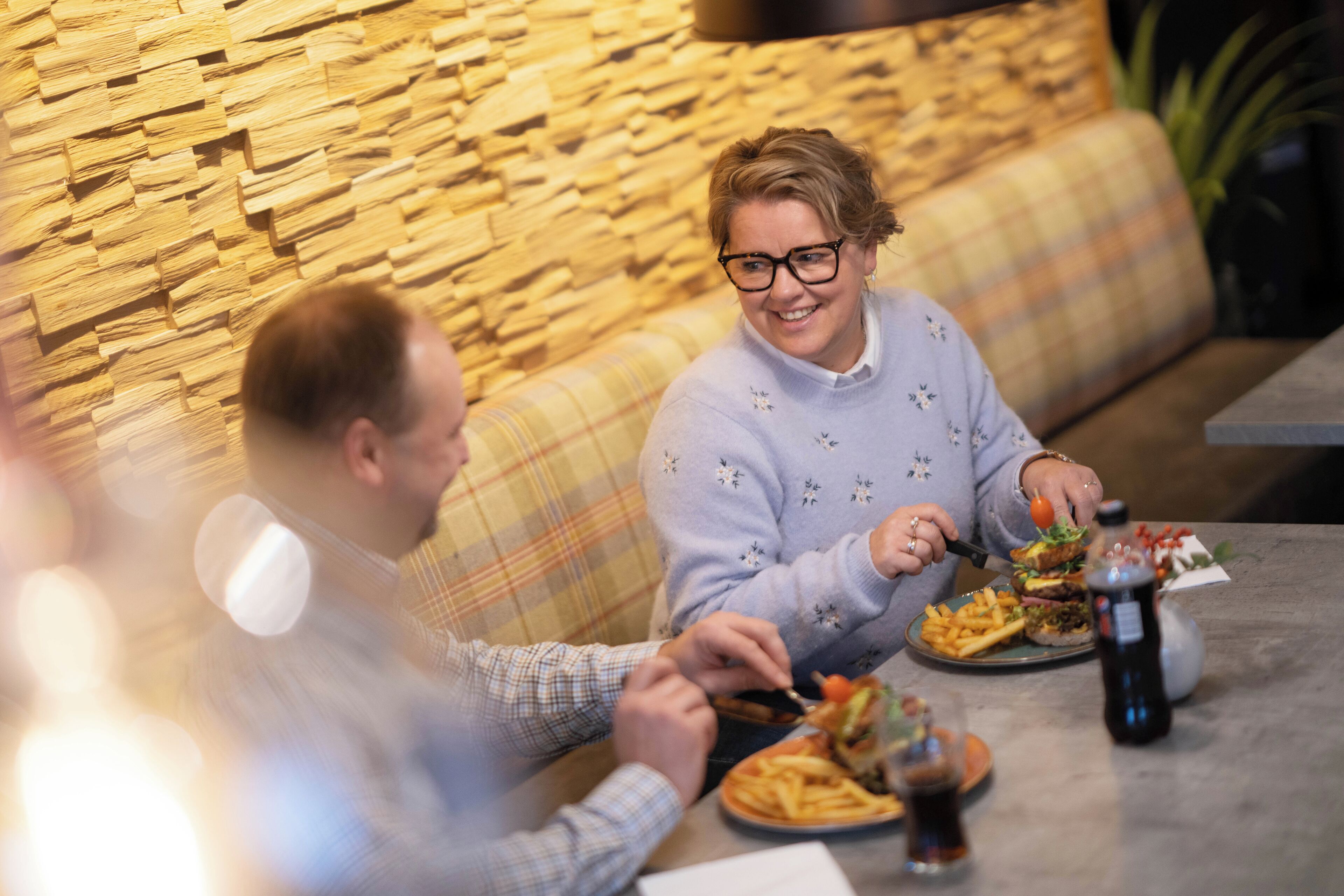 Un coin repas avec un mur en pierre, un canapé et une table garnie de plats et de boissons.