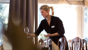 En person arrangerer vinglas på et bord i en restaurant.