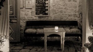 L’intérieur est fait de murs en pierre, avec un banc en bois, une petite table et une lanterne suspendue. Une pancarte sur le mur porte l’inscription suivante : « Il est toujours temps de prendre un verre de vin. »