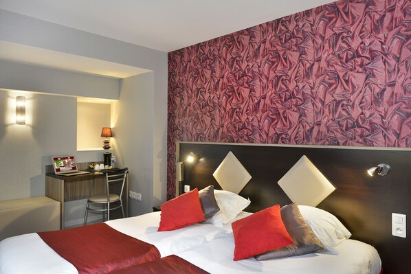 A hotel room with a bed, a desk, and a chair.