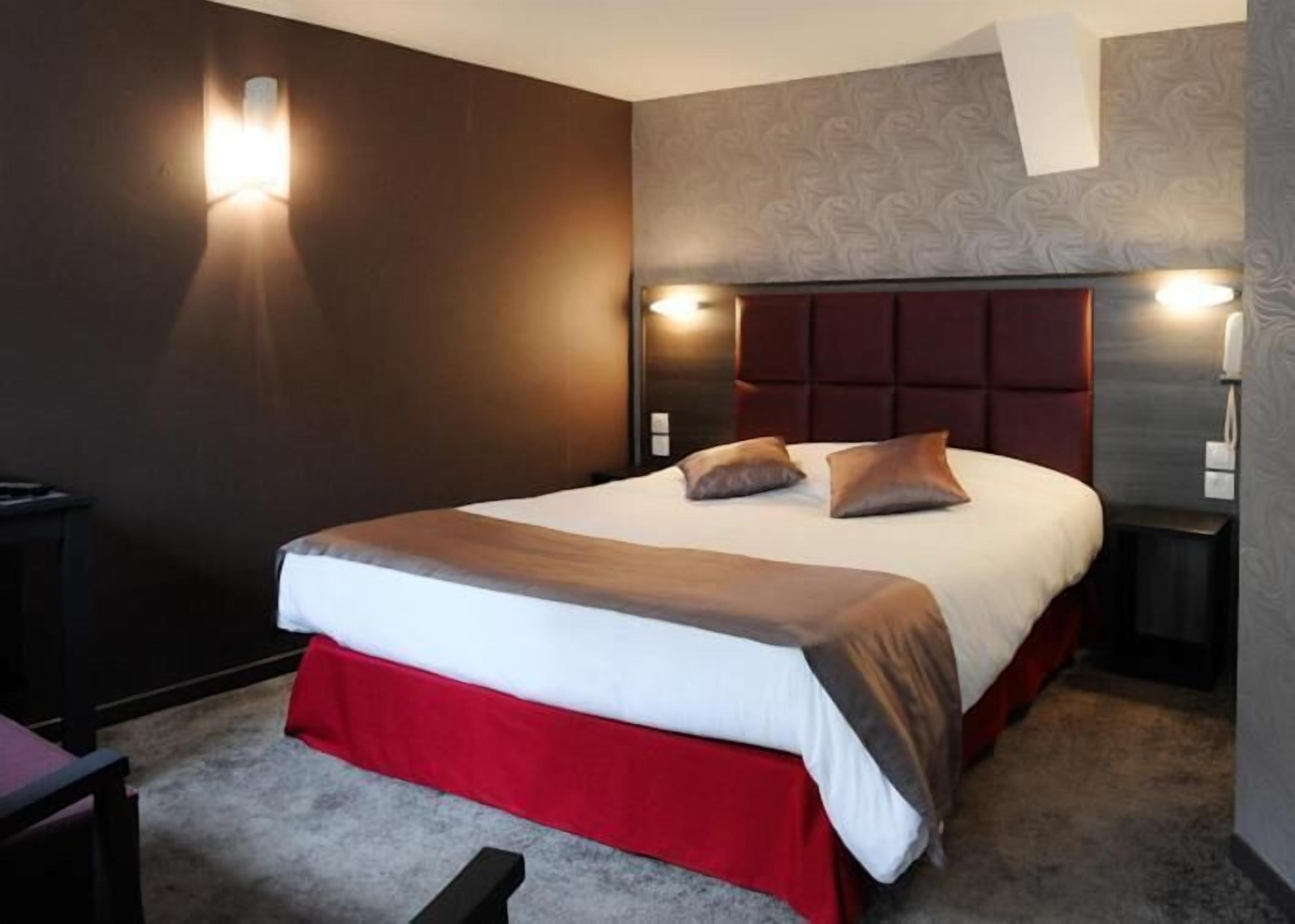 Una habitación de hotel con una cama grande, dos mesitas de noche y una pared de acento roja.