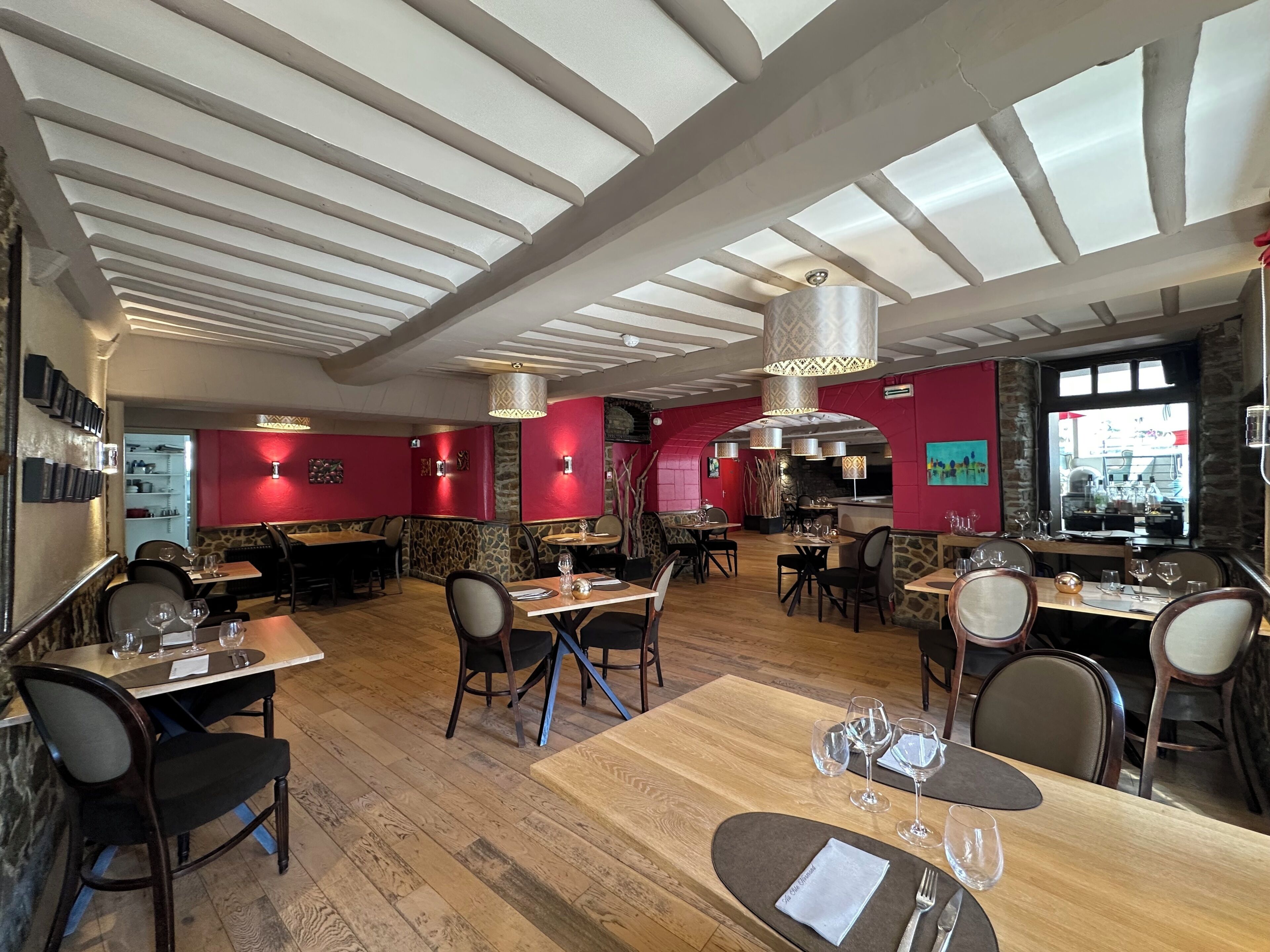 Interior de restaurante con suelo de madera, paredes rojas y varias mesas de comedor.