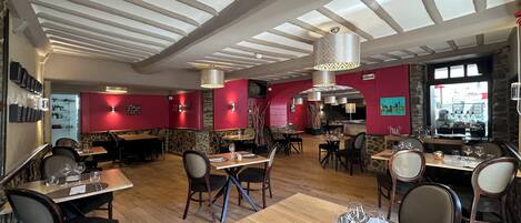 Interior de restaurante con suelo de madera, paredes rojas y varias mesas de comedor.