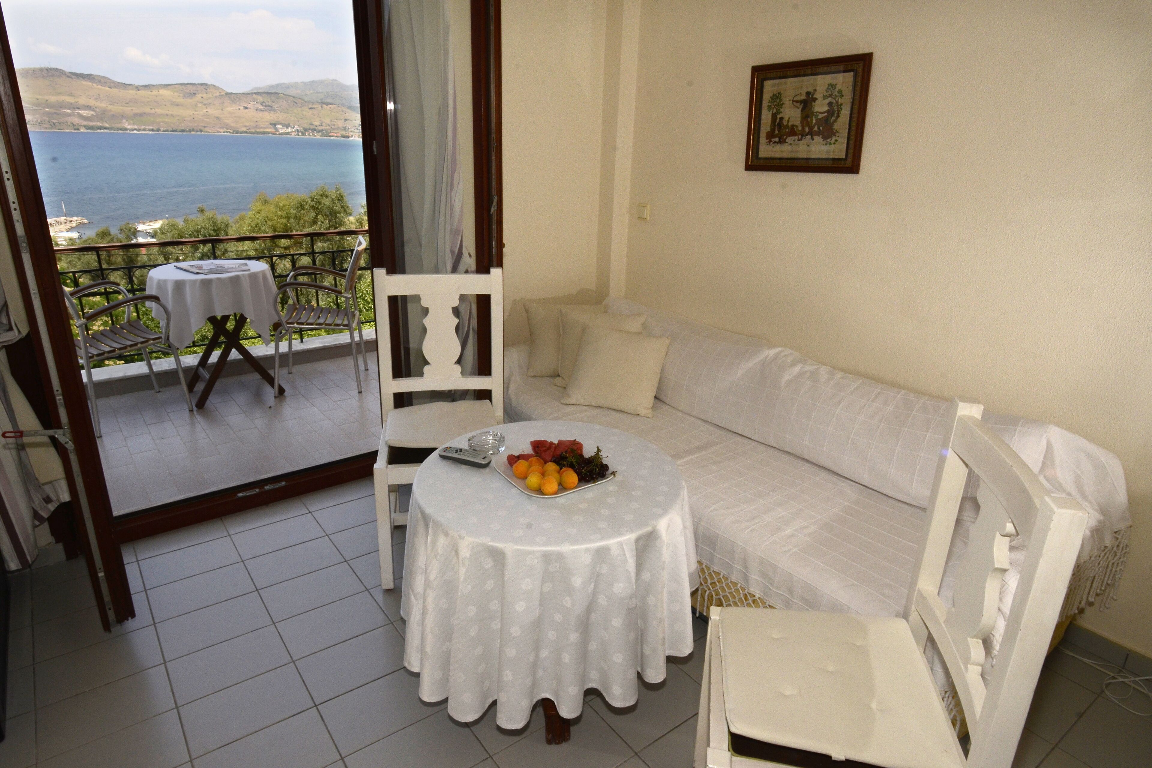 A balcony with a table and chairs, a sofa, and a view of the sea.