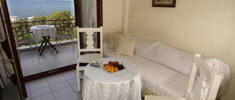 A balcony with a table and chairs, a sofa, and a view of the sea.