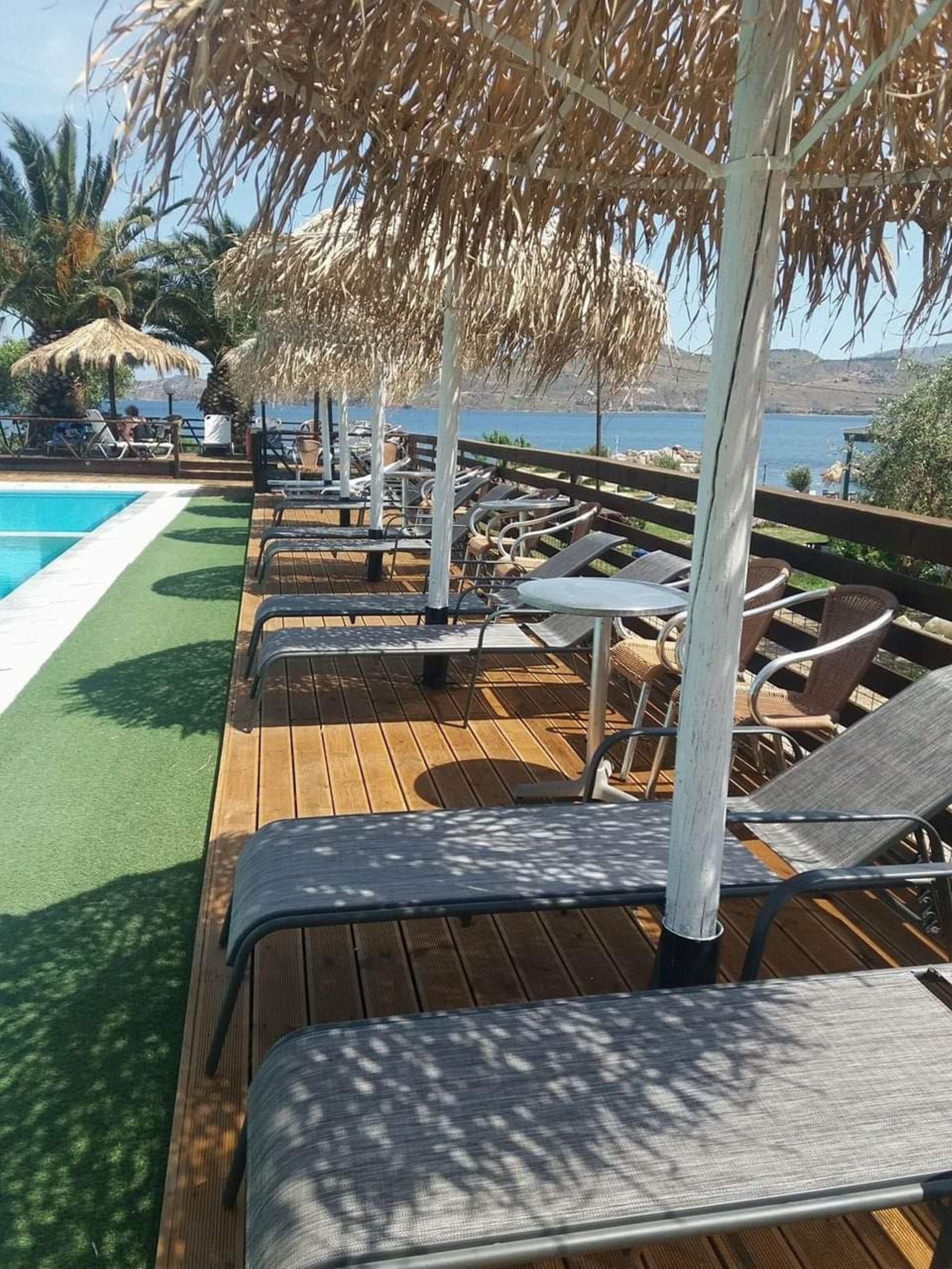 A wooden deck with lounge chairs and a pool, overlooking a body of water.