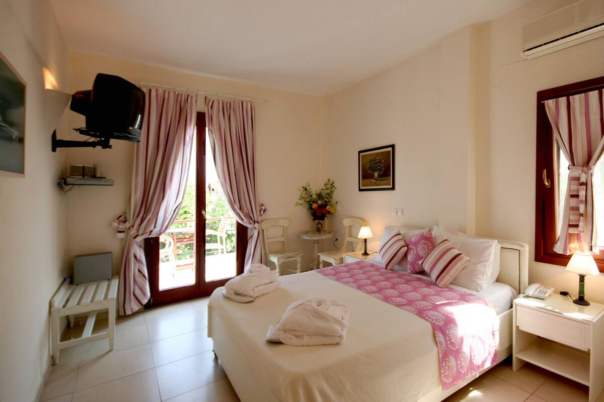 A hotel room with a bed, bedside table, and a television mounted on the wall.