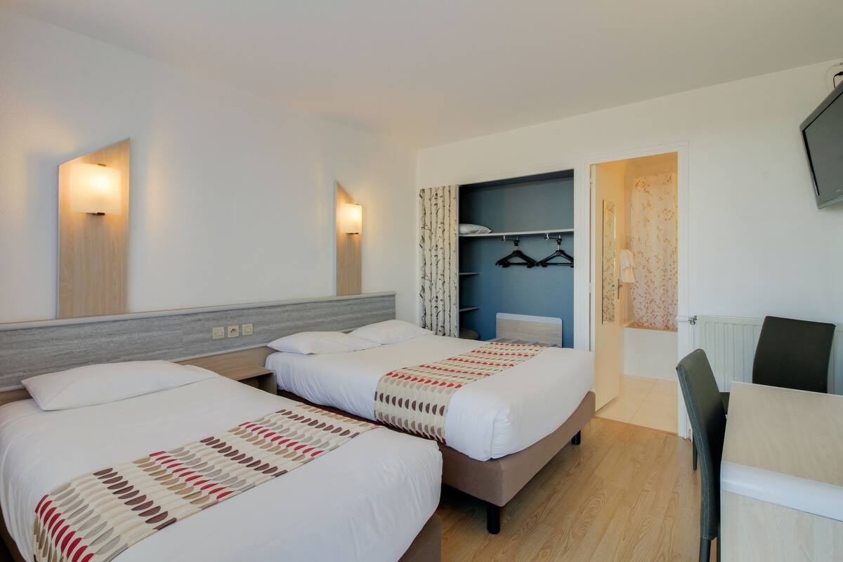 Une chambre d’hôtel avec deux lits, un coin salon, une armoire et un téléviseur.