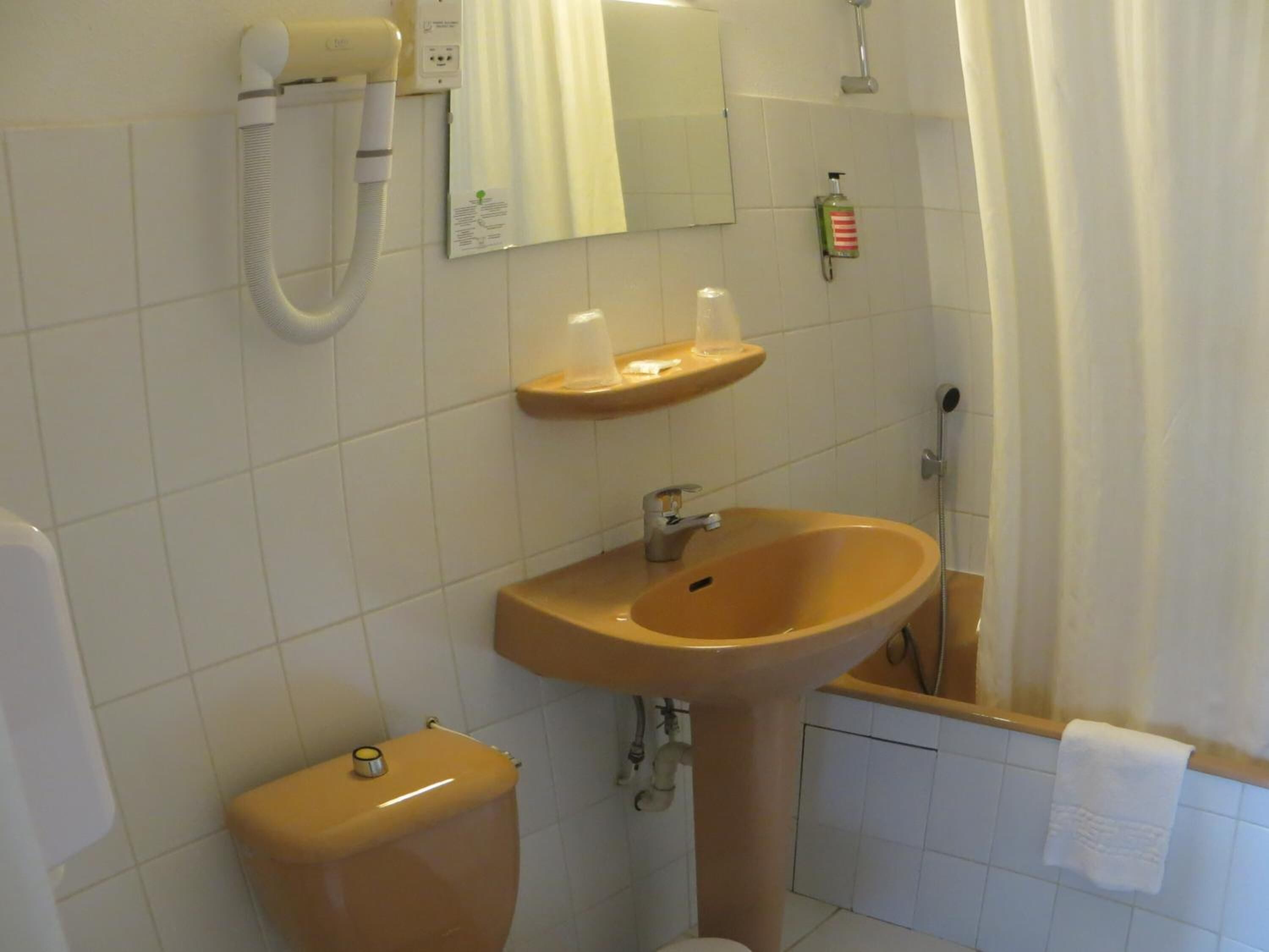 Ein Badezimmer mit Waschbecken, Spiegel, Toilette und Dusche.