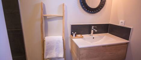 A bathroom with a wooden vanity, a sink, a mirror, and a towel rack.