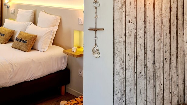 Une chambre à coucher comprenant un lit, des oreillers, un luminaire fixé au mur et un élément décoratif mural.