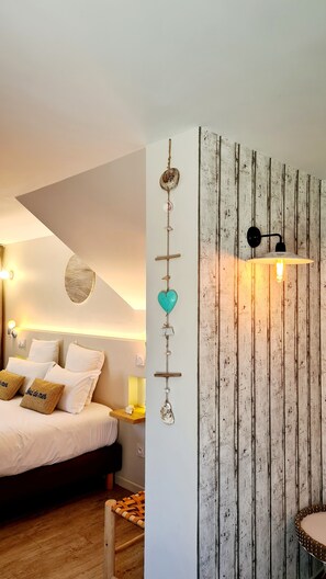Un dormitorio con cama, almohadas, una lámpara fijada a la pared y un adorno mural.